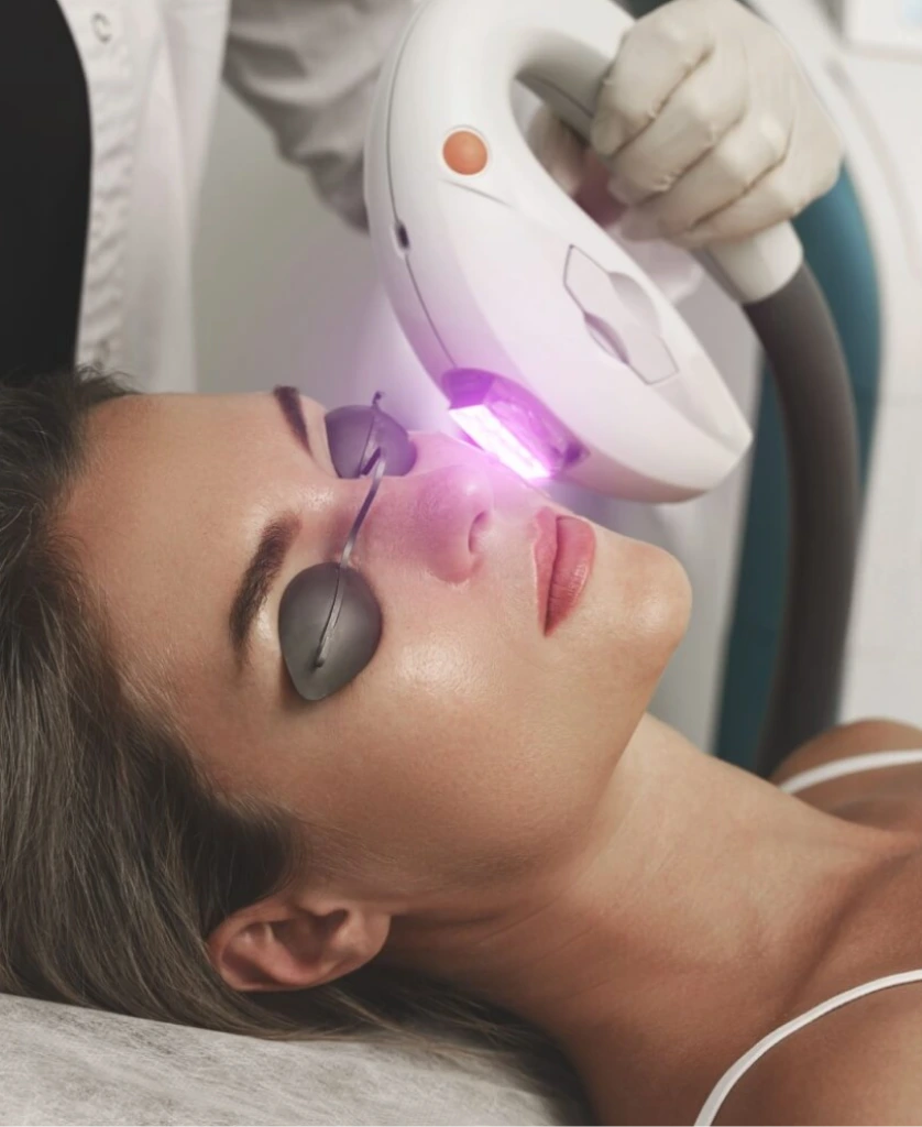 Practitioner administering IPL photofacial treatment to patient's face with handheld device
