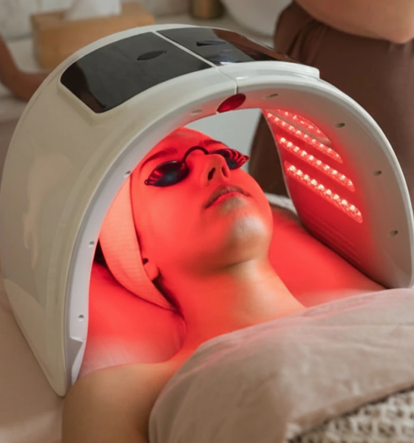 Person receiving LED light therapy treatment with red light mask on face