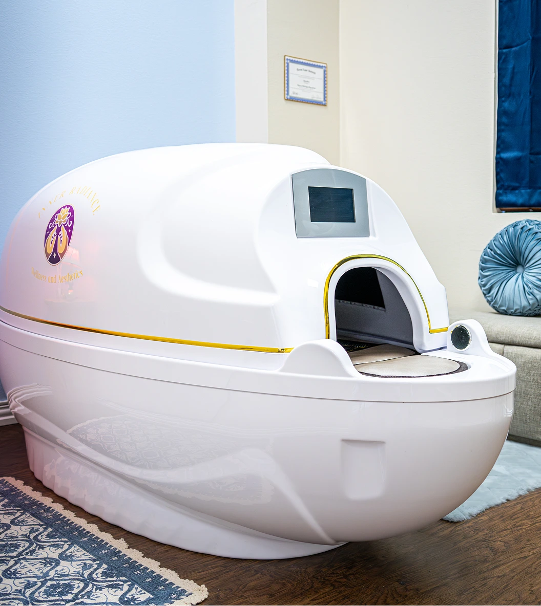 White wellness capsule pod with digital control screen in spa treatment room with blue accents and framed certification on wall