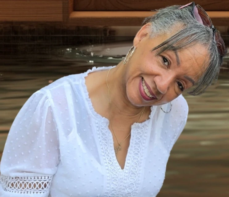 Smiling woman with gray hair wearing white blouse indoors